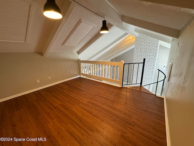 bonus room featuring dark wood-style floors, a textured ceiling, baseboards, and vaulted ceiling with beams