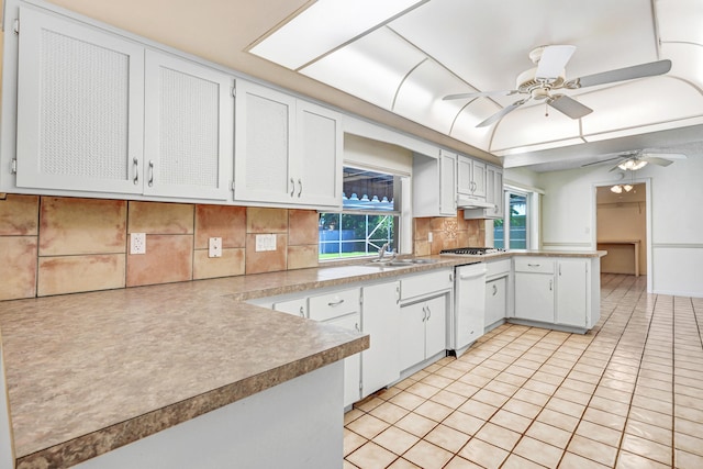 kitchen with backsplash, white dishwasher, sink, white cabinets, and light tile patterned flooring