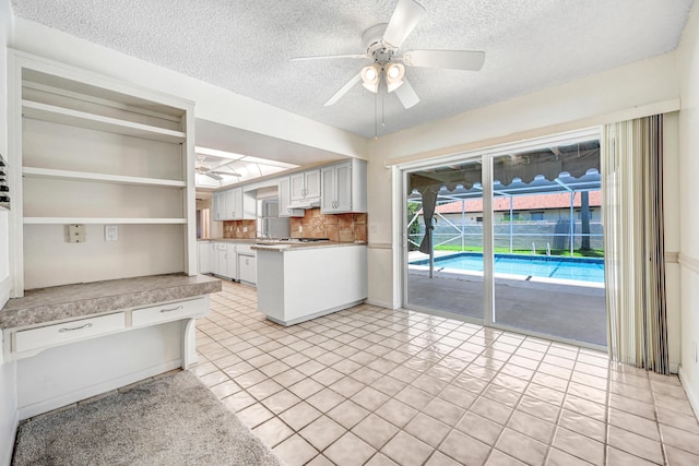 kitchen with white cabinets, ceiling fan, light tile patterned floors, and a textured ceiling