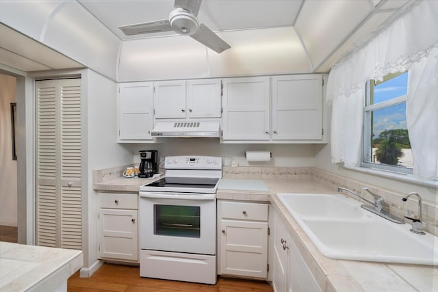 kitchen featuring electric range, sink, and white cabinets