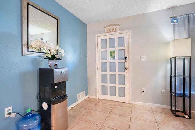 doorway to outside featuring light tile patterned floors and a textured ceiling