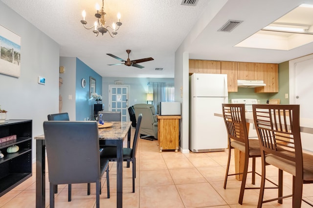 dining room with ceiling fan with notable chandelier, light tile patterned floors, and a textured ceiling