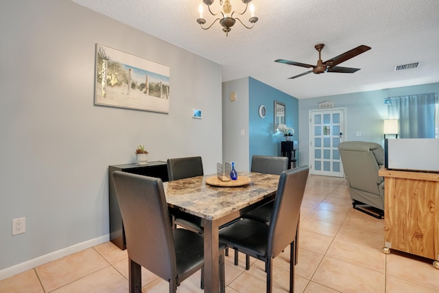 tiled dining space featuring a textured ceiling and ceiling fan with notable chandelier