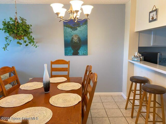 tiled dining area featuring a textured ceiling and a notable chandelier