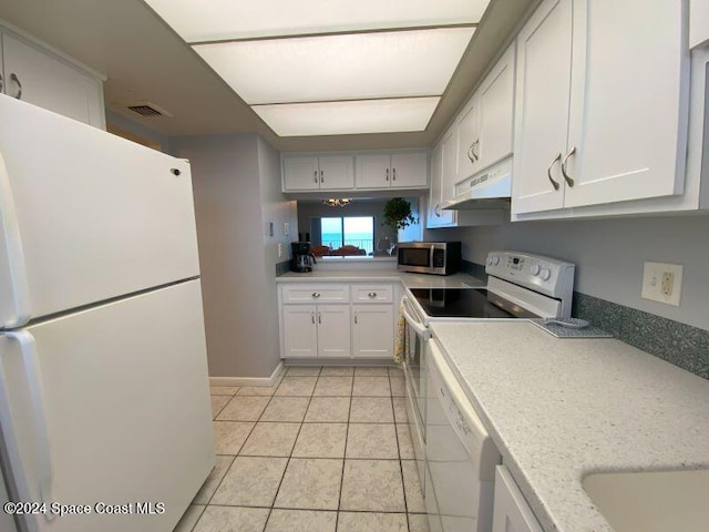 kitchen with white appliances, white cabinetry, light stone countertops, and light tile patterned floors