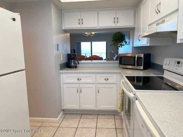 kitchen with white appliances, white cabinets, an inviting chandelier, and light tile patterned floors