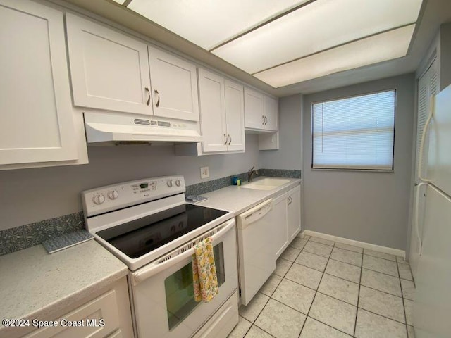 kitchen featuring white appliances, sink, light tile patterned floors, and white cabinetry