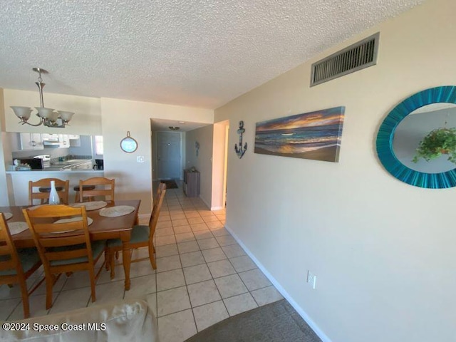 7520 Ridgewood Ave Unit 507, Cape Canaveral, FL 32920 - dining room with light tile patterned floors, a chandelier, a textured ceiling, and baseboards