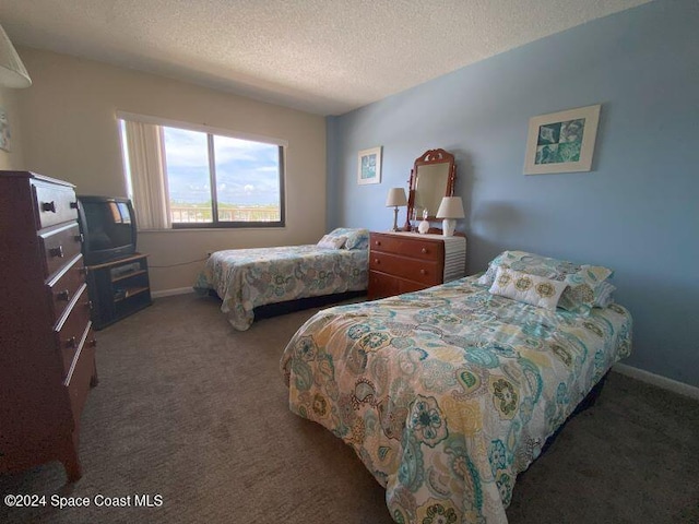 bedroom featuring a textured ceiling and dark colored carpet