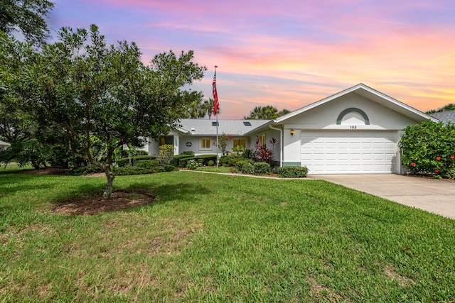 ranch-style home with a garage and a lawn