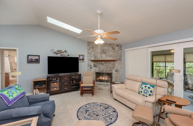 living room featuring light tile patterned flooring, vaulted ceiling, a textured ceiling, ceiling fan, and a fireplace