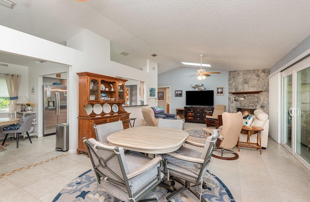 tiled dining area featuring a fireplace, a textured ceiling, vaulted ceiling, and ceiling fan