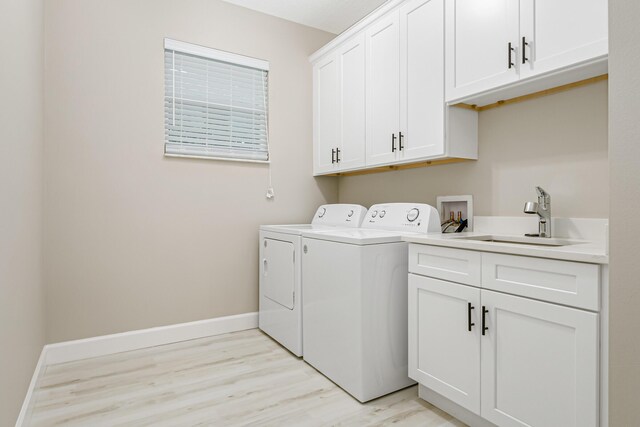 clothes washing area featuring light hardwood / wood-style flooring, cabinets, washer and clothes dryer, and sink