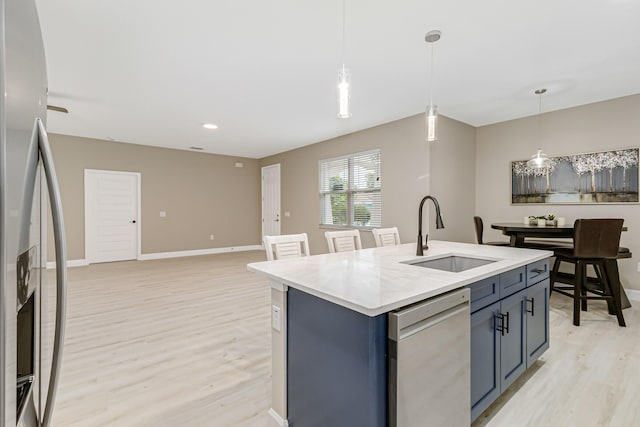 kitchen featuring blue cabinetry, a kitchen island with sink, decorative light fixtures, appliances with stainless steel finishes, and sink