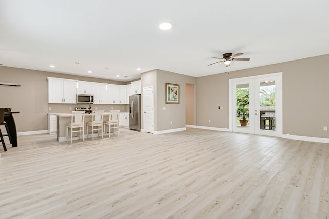 unfurnished living room featuring french doors, light wood-type flooring, and ceiling fan