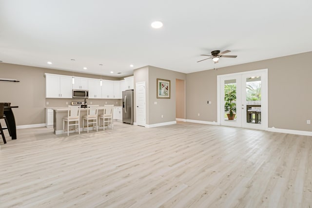 unfurnished living room featuring light hardwood / wood-style floors, ceiling fan, and french doors