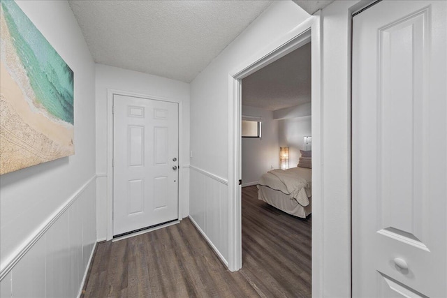 hall with dark hardwood / wood-style floors and a textured ceiling