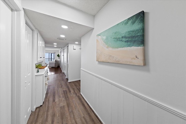 hall featuring a textured ceiling and dark hardwood / wood-style floors