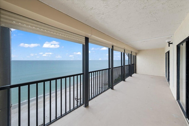 balcony with a water view and a view of the beach