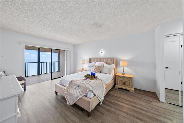 bedroom with a closet, dark hardwood / wood-style flooring, access to exterior, and a textured ceiling