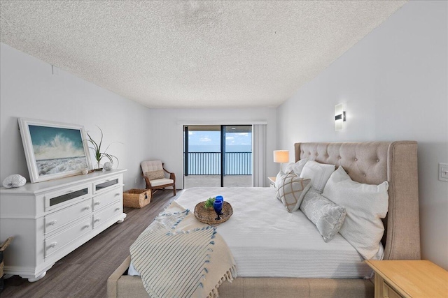 bedroom with a textured ceiling, access to outside, and dark hardwood / wood-style floors