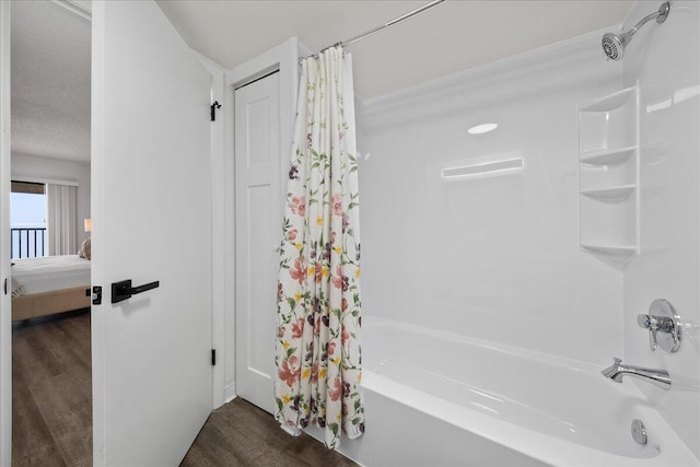 bathroom with hardwood / wood-style flooring, shower / bathtub combination with curtain, and a textured ceiling