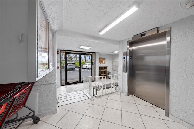 interior space with elevator, a textured ceiling, and light tile patterned floors