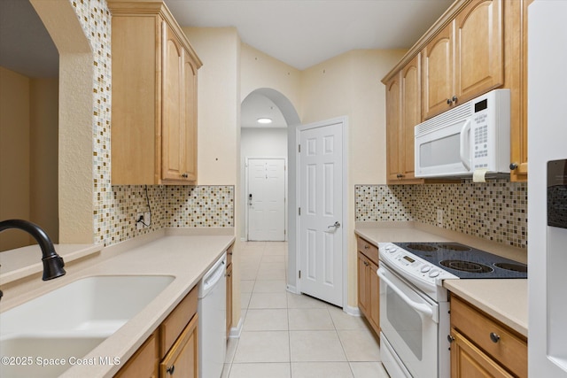 kitchen featuring white appliances, light brown cabinetry, sink, and light tile patterned floors