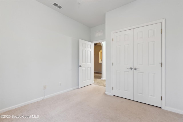 unfurnished bedroom with light colored carpet and a closet