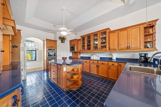 kitchen featuring stainless steel double oven, a kitchen island, sink, a raised ceiling, and built in microwave