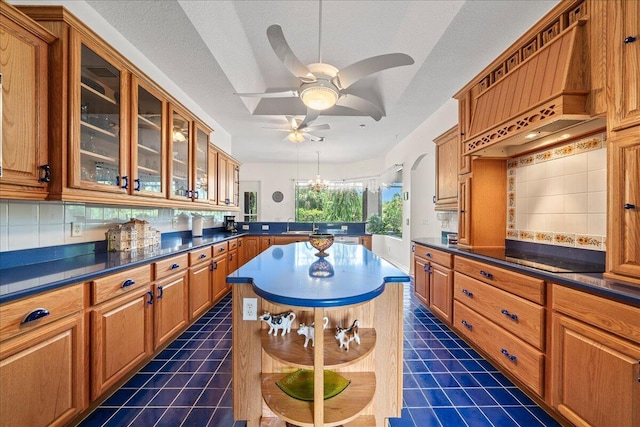 kitchen with premium range hood, backsplash, a textured ceiling, and a kitchen island