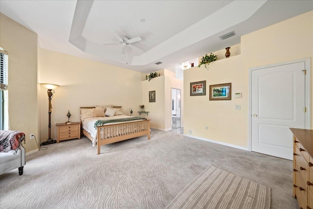 bedroom featuring ceiling fan, light colored carpet, and a raised ceiling