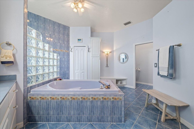 bathroom with ceiling fan, tiled tub, tile patterned floors, and vanity