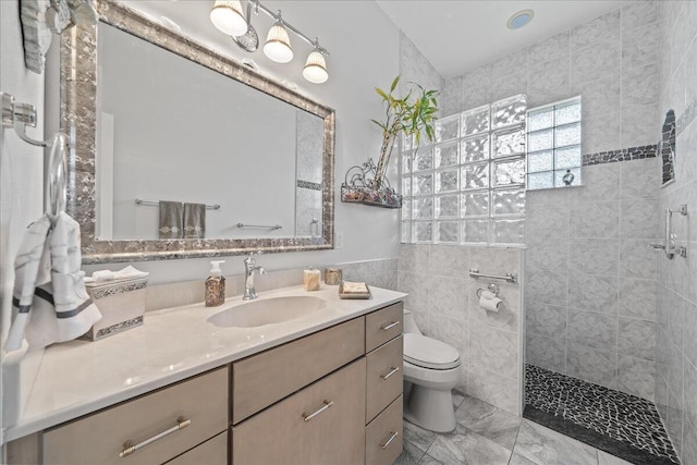 bathroom with a tile shower, toilet, and vanity