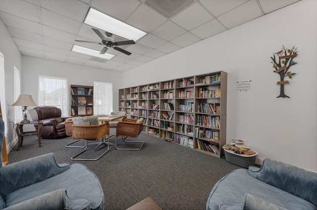 carpeted living room featuring ceiling fan and a drop ceiling