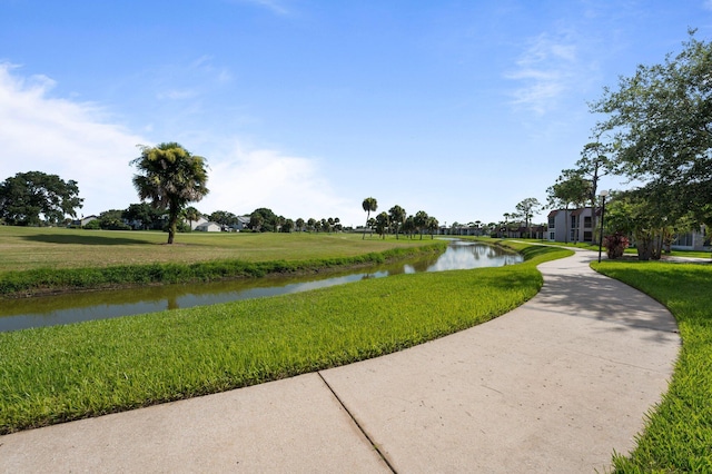 view of home's community with a water view and a lawn