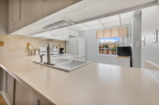 kitchen with a drop ceiling, white appliances, white cabinets, sink, and decorative backsplash