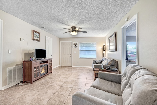 living room featuring a textured ceiling, ceiling fan, and light tile patterned floors