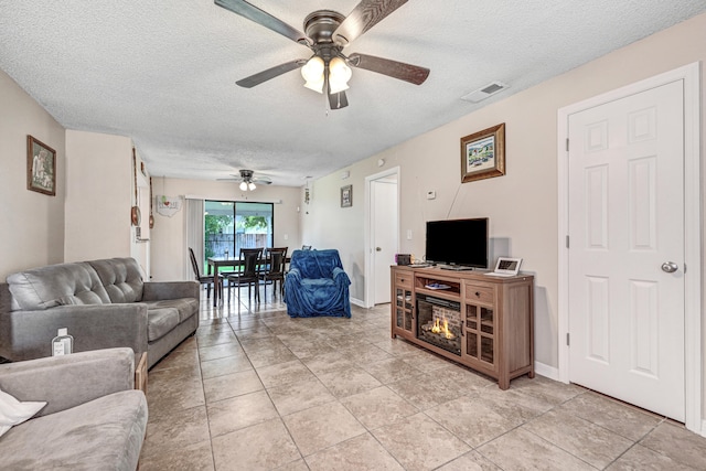 living room with a textured ceiling, light tile patterned floors, and ceiling fan