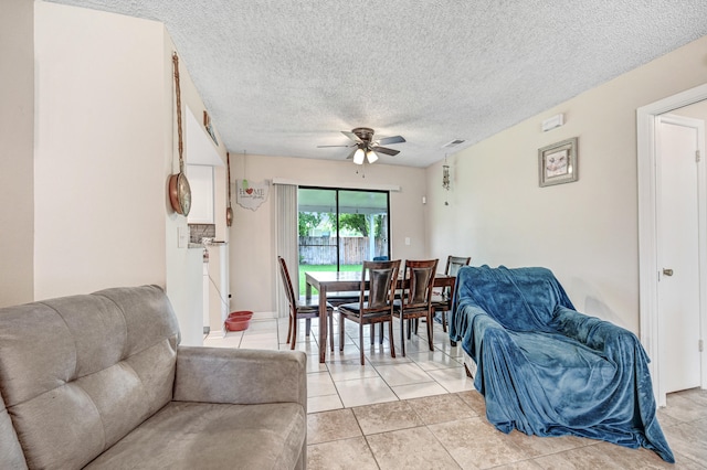 living room featuring a textured ceiling, ceiling fan, and light tile patterned floors