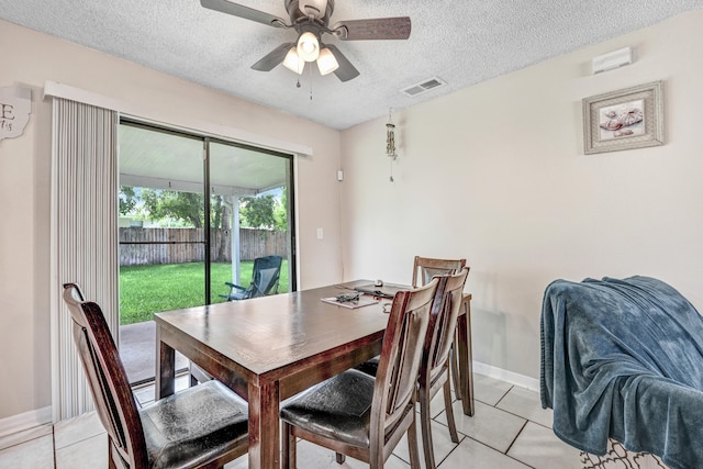 tiled dining space featuring a textured ceiling and ceiling fan