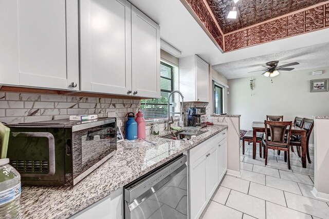 kitchen with dishwasher, backsplash, light stone countertops, white cabinetry, and ceiling fan