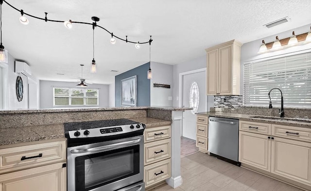 kitchen with appliances with stainless steel finishes, ceiling fan, sink, pendant lighting, and cream cabinetry