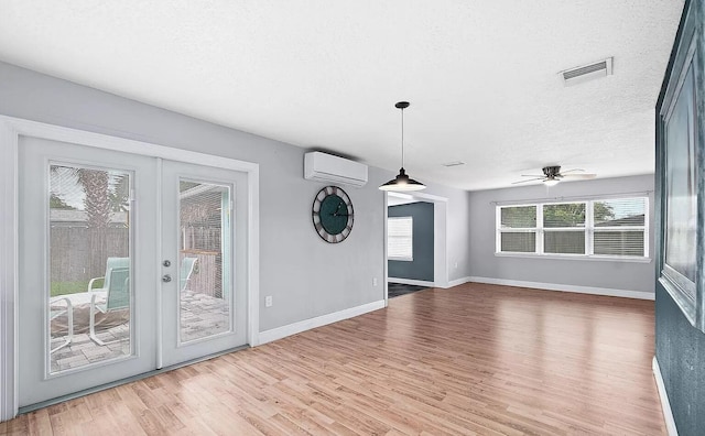 interior space featuring ceiling fan, french doors, an AC wall unit, wood-type flooring, and a textured ceiling