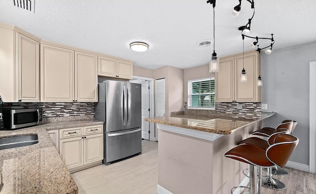 kitchen featuring cream cabinets, stone countertops, and appliances with stainless steel finishes