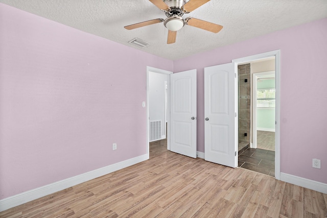 unfurnished bedroom featuring a textured ceiling, light hardwood / wood-style floors, ceiling fan, and ensuite bathroom