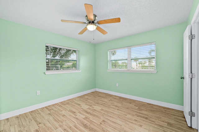 unfurnished room with a textured ceiling, light wood-type flooring, and ceiling fan