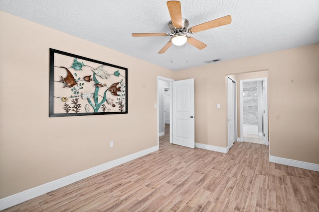 unfurnished room featuring ceiling fan, light wood-type flooring, and a textured ceiling