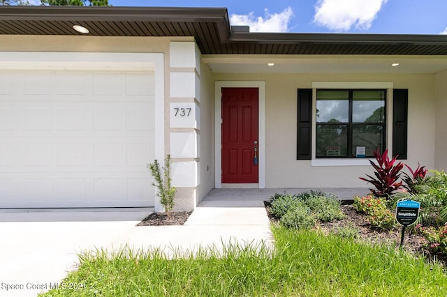 1071 Grapefruit Rd SE, Palm Bay, FL 32909 - entrance to property with an attached garage, covered porch, and stucco siding