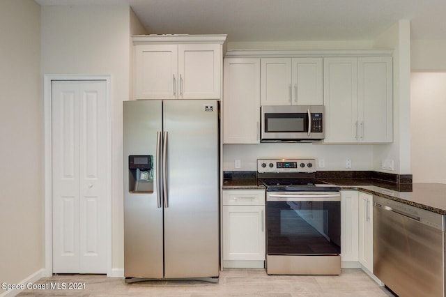 1071 Grapefruit Rd SE, Palm Bay, FL 32909 - kitchen with stainless steel appliances, light wood-type flooring, white cabinetry, and dark stone countertops